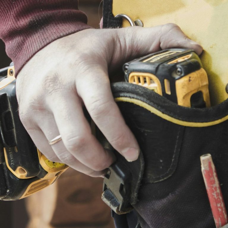 Dépannage électrique rapide à Paris Main tenant d'une ceinture à outils avec un appareil de mesure services d'intervention électrique à Paris.